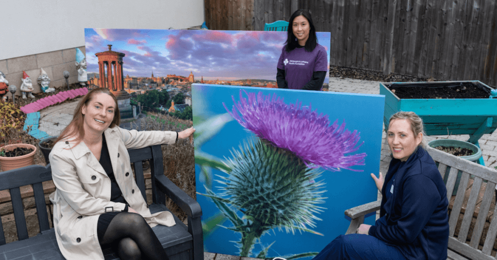 Women holding a painting of a thistle