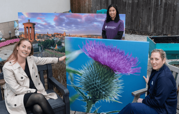 Women holding a painting of a thistle