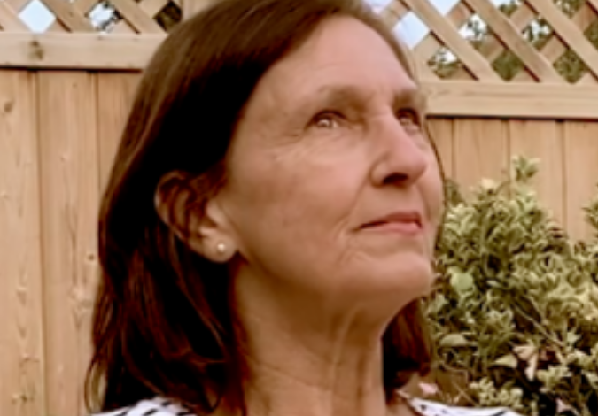 NHS Lothian staff member in a garden, head up, thinking