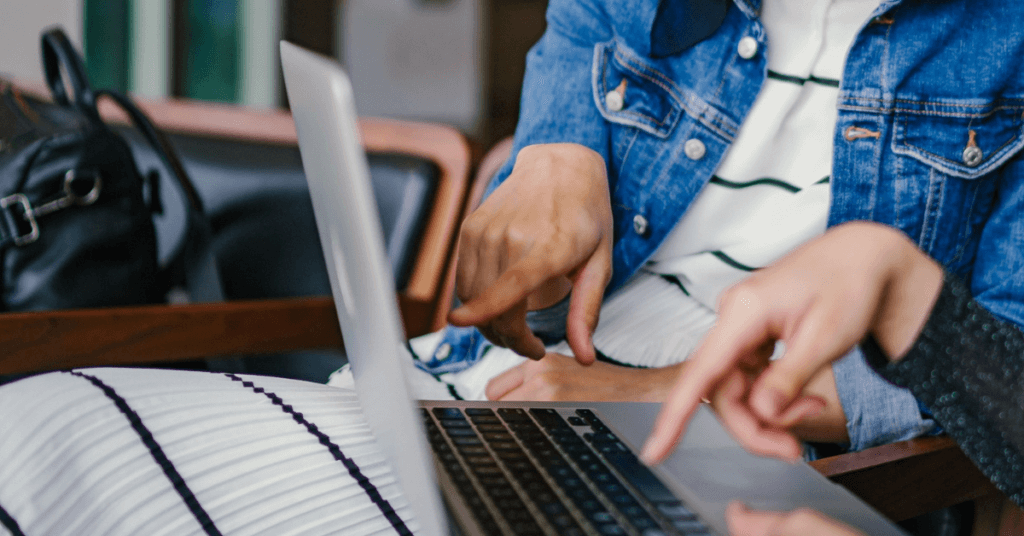 Two people sat at a laptop pointing at the screen