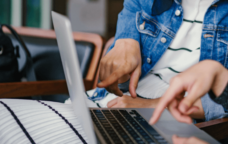 Two people sat at a laptop pointing at the screen