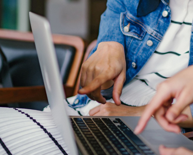 Two people sat at a laptop pointing at the screen