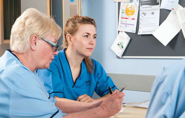 Nurses sat down at table with pen and paper in thought
