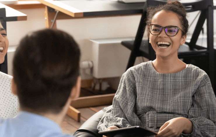 Work Colleagues sat together in an office smiling