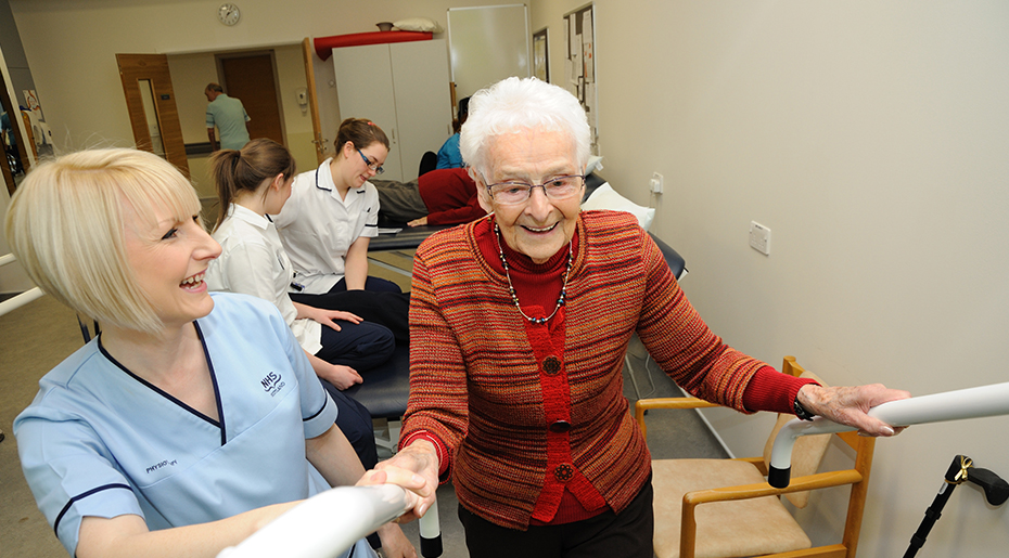 Nurse helping elderly lady up the stairs inside ward