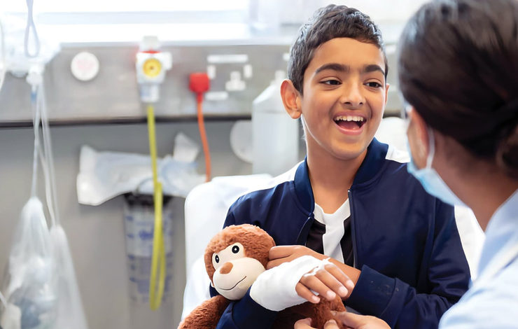 Boy smiling at the camera with a bandage on his arm cuddling a monkey