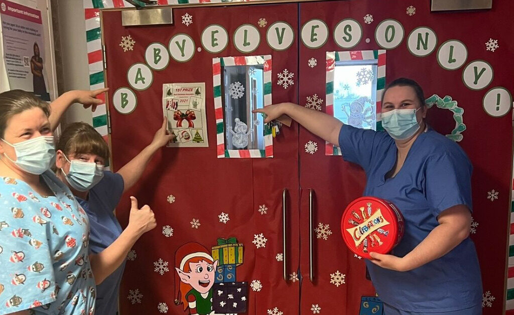 NHS Lothian staff stood by the entrance to the special care baby unit at St Johns. On the door is says "Baby Elves Only"