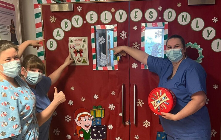 NHS Lothian staff stood by the entrance to the special care baby unit at St Johns. On the door is says "Baby Elves Only"