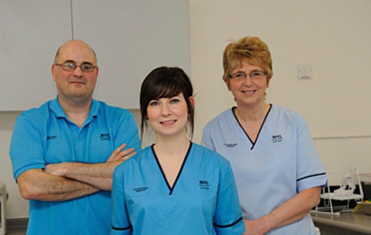 Three NHS Staff members in uniform facing the camera