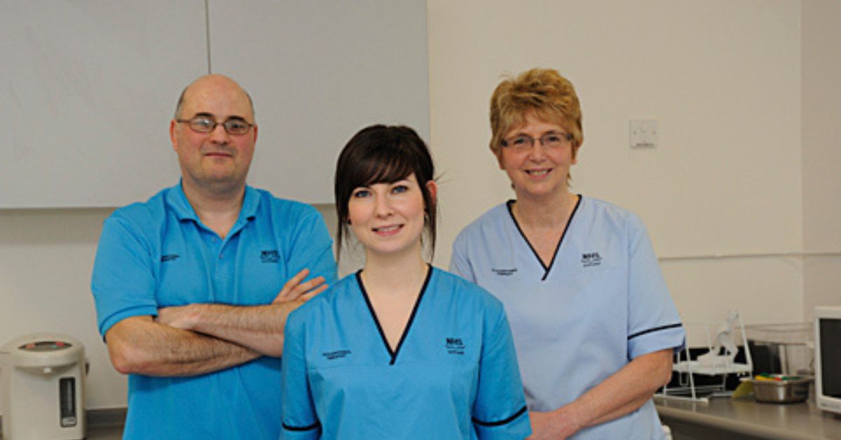 Three NHS Staff members in uniform facing the camera