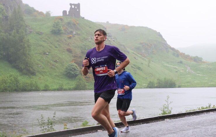 EMF runner, Ben, with his NHS Lothian Charity t-shirt on running on the road past water