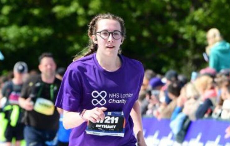 EMF runner, Beth, running past the crowds in her NHS Lothian Charity t-shirt