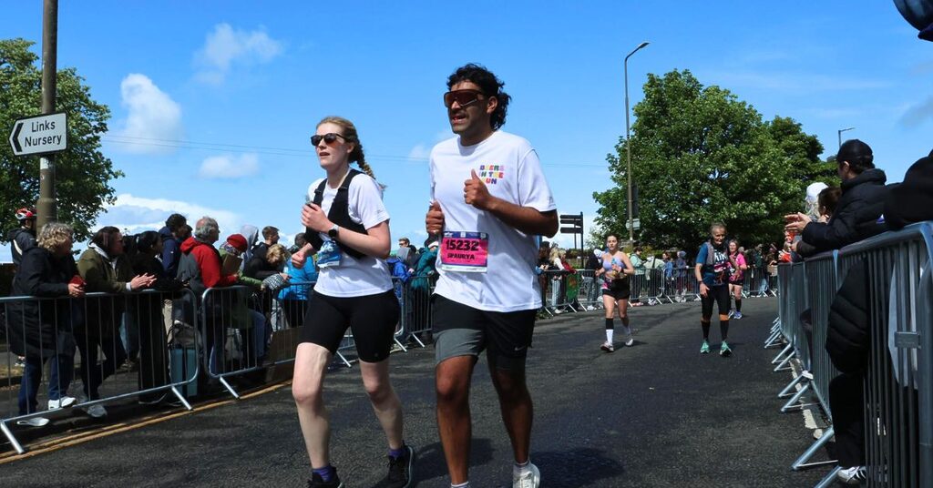 two EMF runners passing the crowds who are standing behind barriers