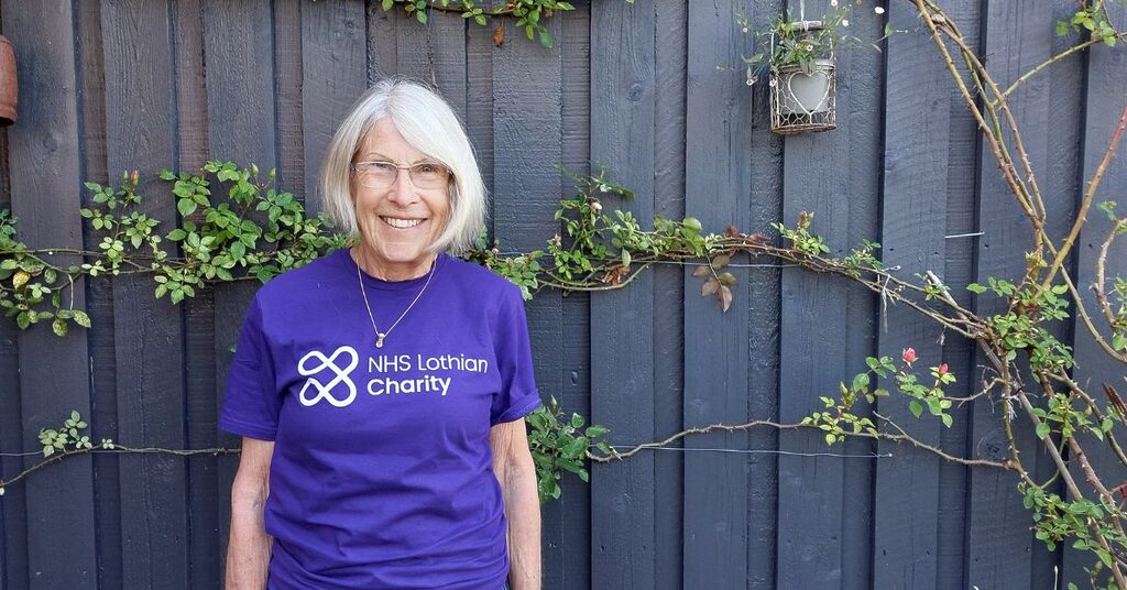 Fundraiser Andrea Stirling wearing her NHS Lothian Charity t-shirt and standing in front of a wall