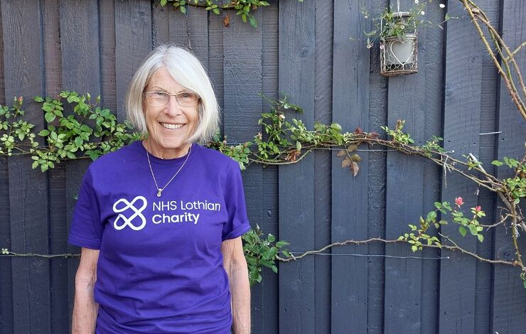 Fundraiser Andrea Stirling wearing her NHS Lothian Charity t-shirt and standing in front of a wall