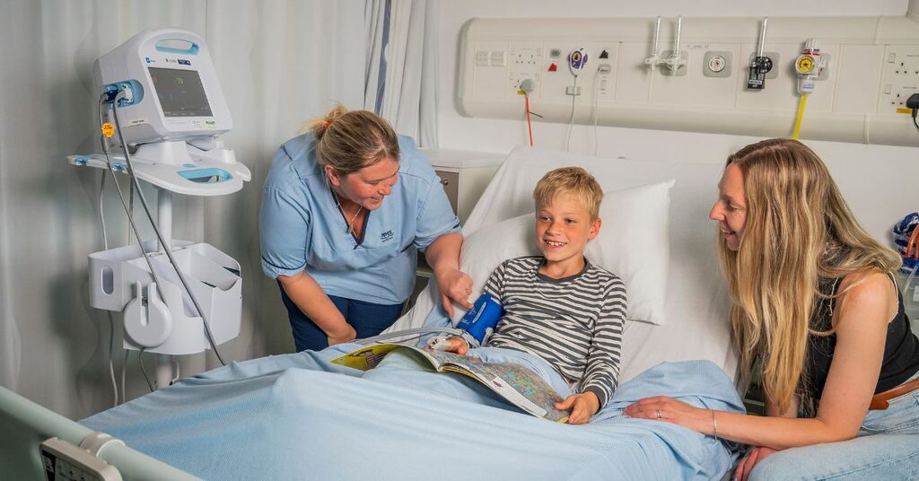 nurse laughing with a patient and their family reading a book